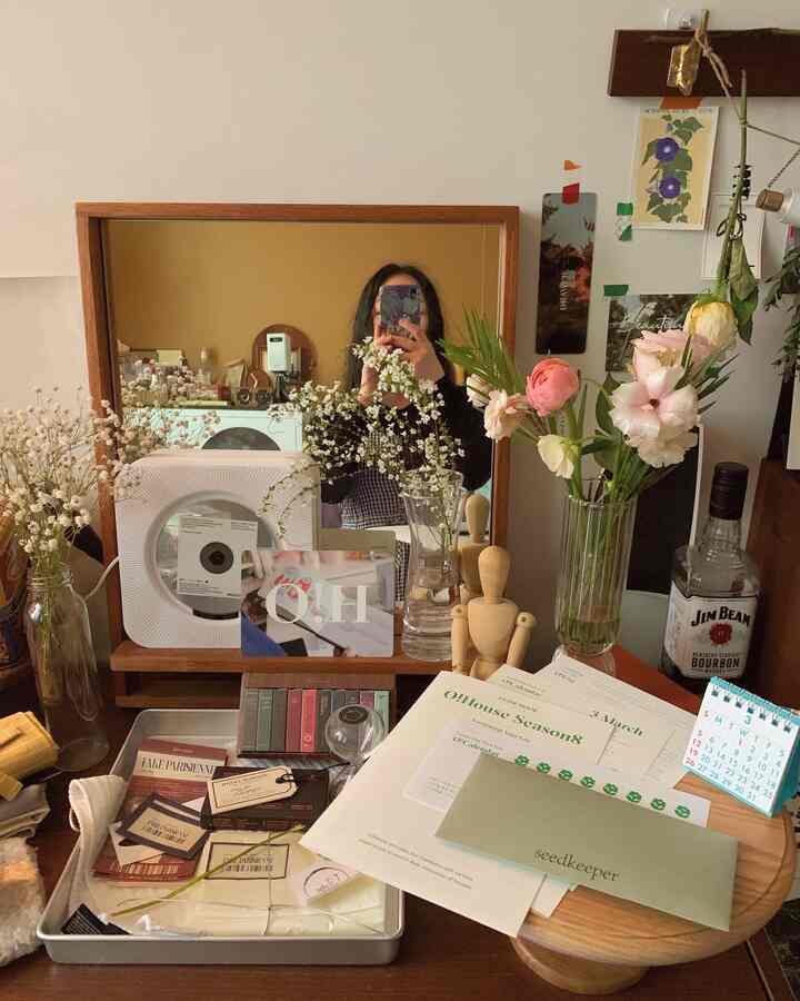Warm vintage bedroom vanity in dark wood tone and white background, featuring pink flowers in glass vases and decorative wall elements