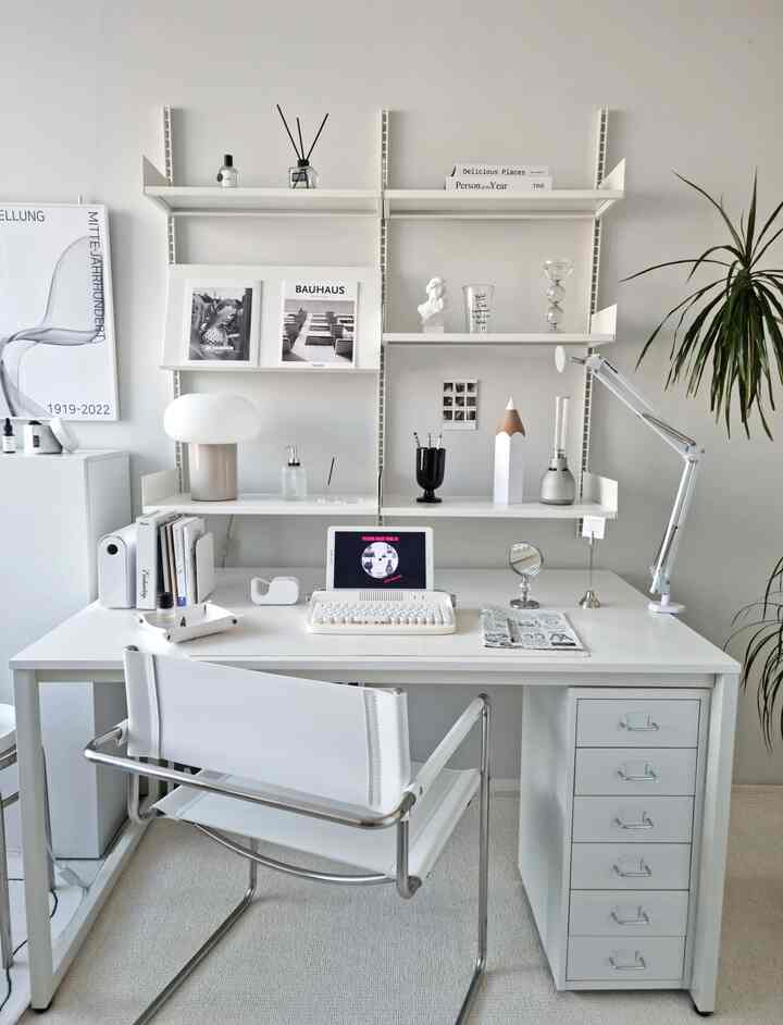 White and light gray toned home office space featuring a white desk, shelves, lighting, and modern minimalistic interior