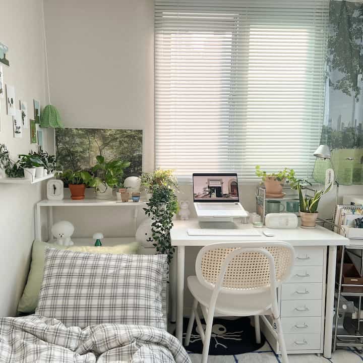 ホワイトトーンのホームオフィス、デスクにノートパソコンと多彩な植物が配置された雰囲気のある作業空間