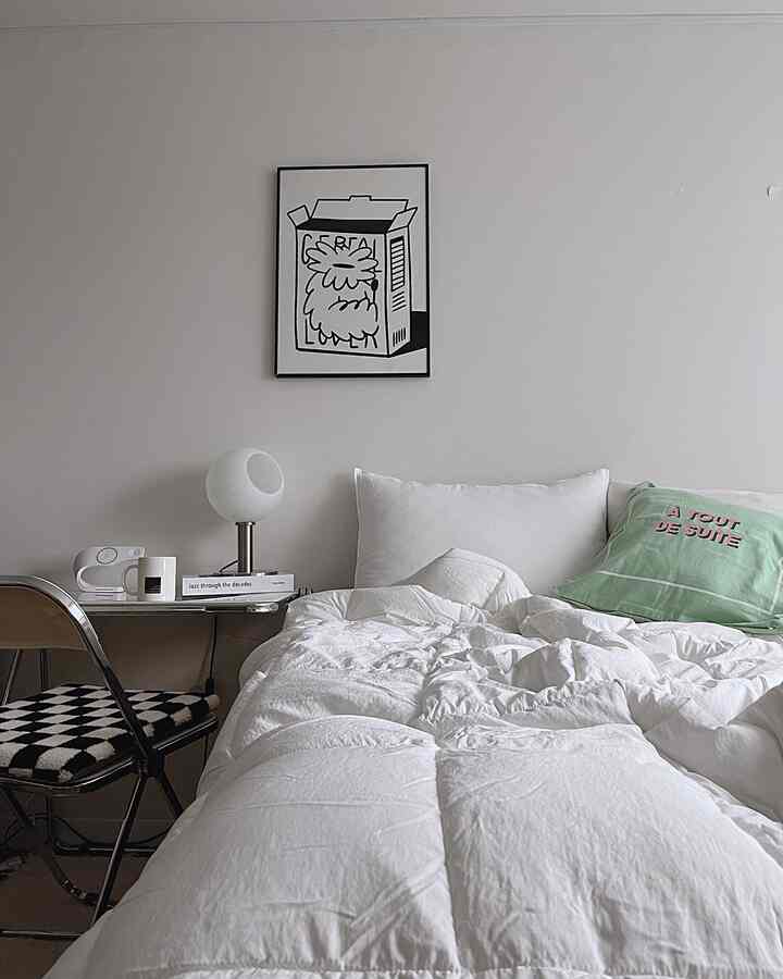 White and beige toned kids' room featuring white bedding and a green cushion, creating a clean and modern atmosphere