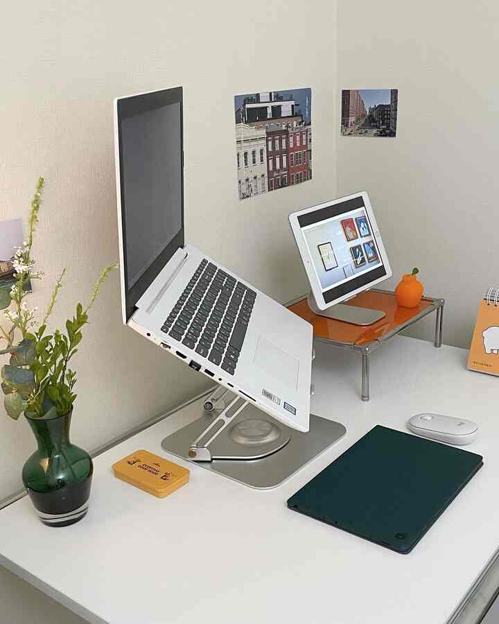 White and silver toned home office featuring a laptop and tablet stand arranged neatly on a clean desk