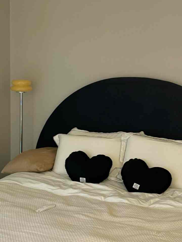Ivory-toned bedroom featuring a bed with black heart-shaped cushions and a simple decor tone
