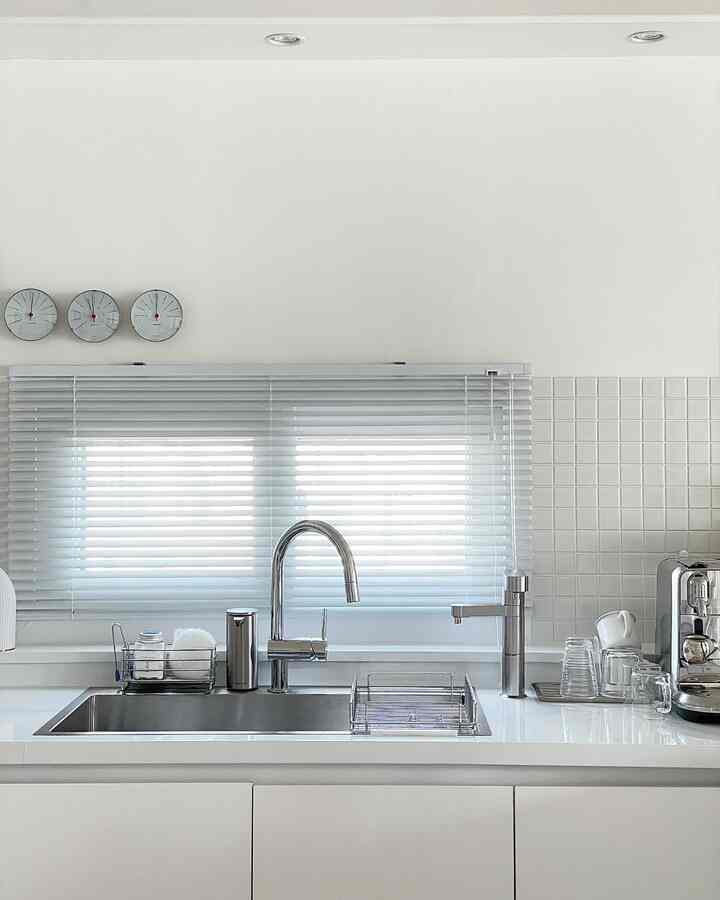 White-toned kitchen space featuring a central sink with stainless steel faucet, creating a clean and bright atmosphere