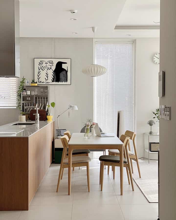 Modern dining room in white and wood tones featuring clean dining table, chairs, and pendant light creating a cozy atmosphere