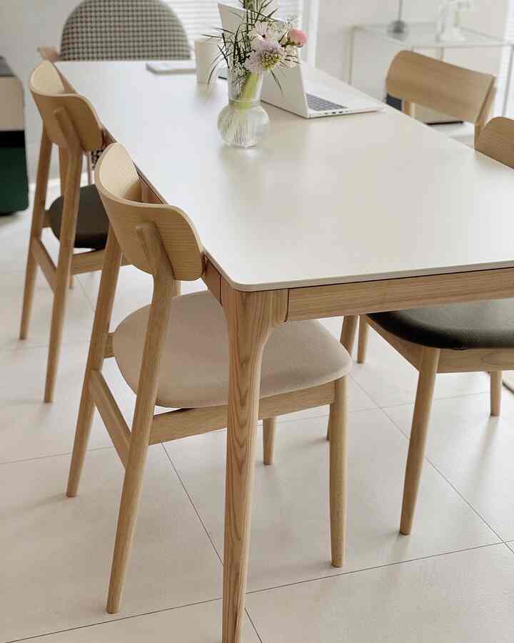 Bright natural-toned dining room featuring wooden chairs and a white dining table in a clean, cozy setting