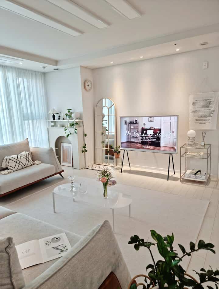 White-toned living room featuring modern sofa and TV stand with clean and cozy interior