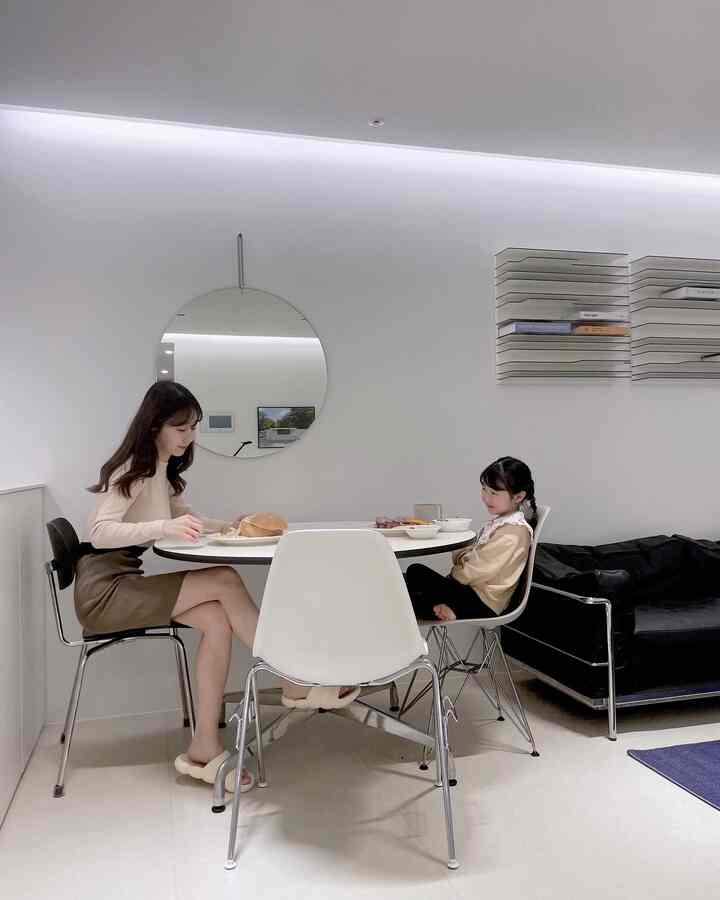 White-toned dining room featuring a round table with Mid-Century Modern dining chairs in a clean, simple space