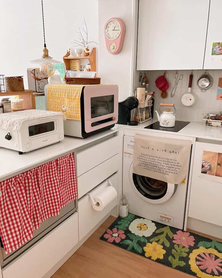 A cozy studio kitchen in white and red tones featuring neat storage solutions and retro-style accessories