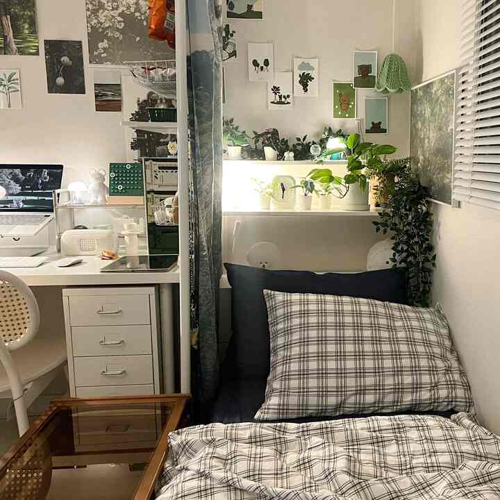 Natural-toned single bedroom and home office space featuring white desk and plants with a cozy atmosphere