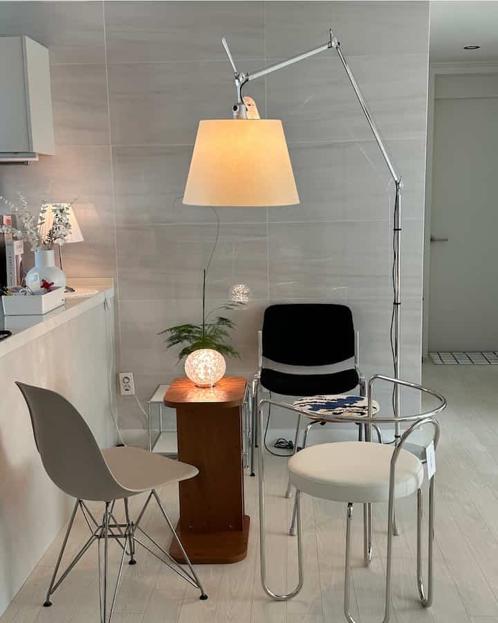 ホワイトとライトブラウンの色調のダイニングルーム、モダンな椅子とフロアランプが配置された雰囲気のあるインテリア