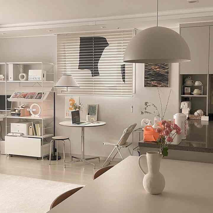 White and beige toned kitchen and home cafe space featuring simple modern furniture and plants with a cozy ambiance