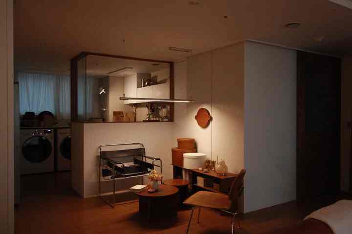 ナチュラルな木目調と白い壁の二人暮らし用キッチンダイニング、モダンなアームチェアと丸テーブルが配置された落ち着いた雰囲気の空間