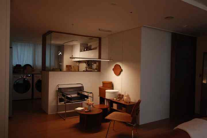 Minimal living room in wood tones and charcoal with metal armchair and round coffee table creating a cozy atmosphere