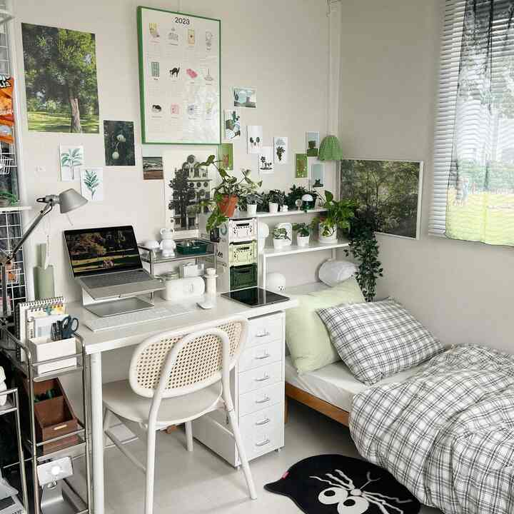 A white and natural-toned bedroom-cum-home office featuring a desk with computer, plants, and cozy decor