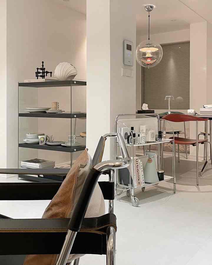 White and black tones with transparent shelves surrounding a pillar between kitchen and living room in a sleek Mid-Century Modern style space