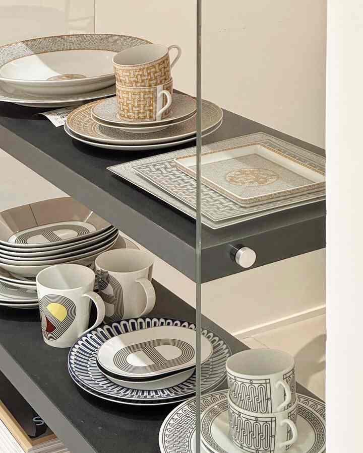 Wood tone and gray-toned kitchen shelves featuring various patterned mugs and plates in a mid-century modern style space