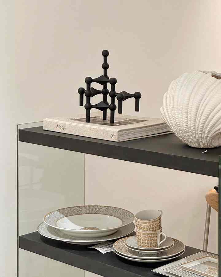 Mid-Century Modern kitchen interior with black shelf displaying white ceramic shell vase, plates, and cups