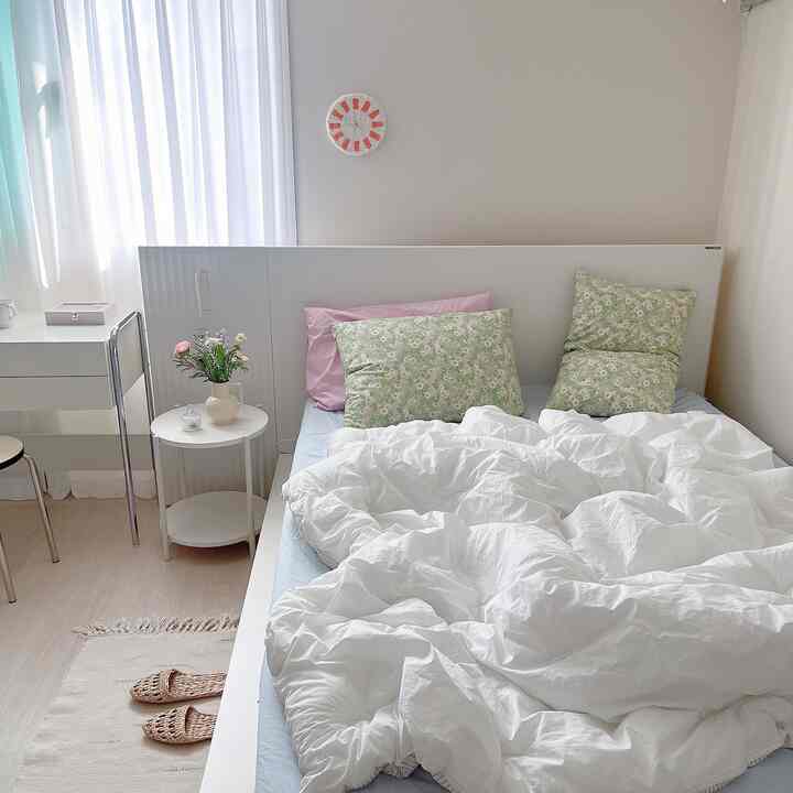White and blue toned bedroom featuring floral pillows and clean white bedding with a natural, fresh atmosphere