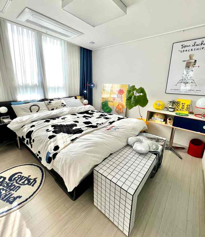 Bright and unique bedroom with white base and black spotted bedding, featuring mid-century modern furniture and colorful accent decor in harmony