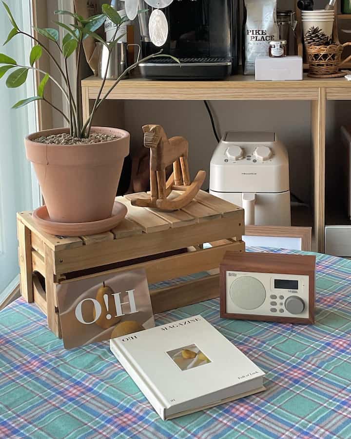 Wood tone kitchen space with blue checked tablecloth, featuring coffee machine and plant in a cozy home cafe style interior
