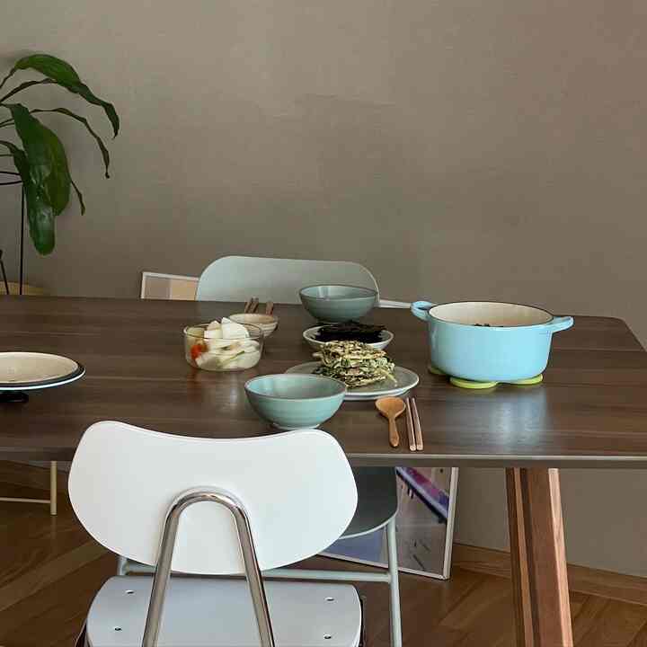 ブラウンの木目調ダイニングルーム、ホワイトのダイニングチェアとブルーの鋳鉄鍋が配されたシンプルで自然な雰囲気のキッチンインテリア