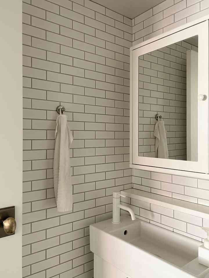 Simple bathroom with clean white tiled walls, white sink, and mirror cabinet creating a fresh atmosphere