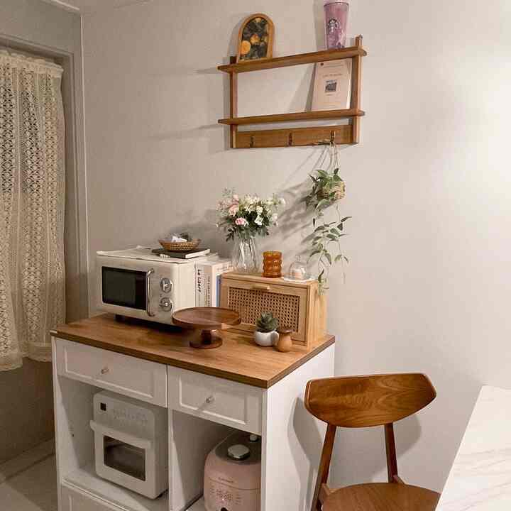 白と木目調が調和したキッチン空間、壁棚と収納キャビネット、ダイニングチェアが温かみのある雰囲気を演出