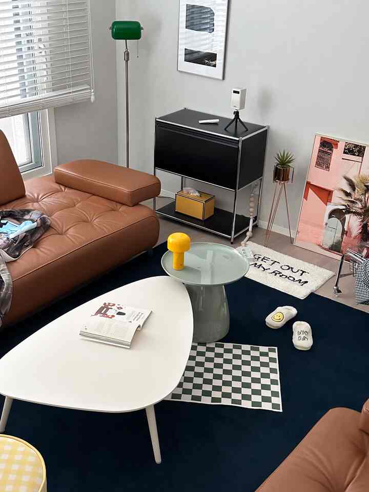 Contemporary living room with brown leather sofa, white coffee table on dark blue rug, accented by modern decor