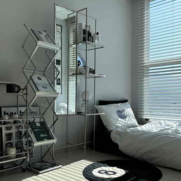 Monotone black and white bedroom space featuring a single bed and mid-century modern storage furniture with a clean, minimal vibe