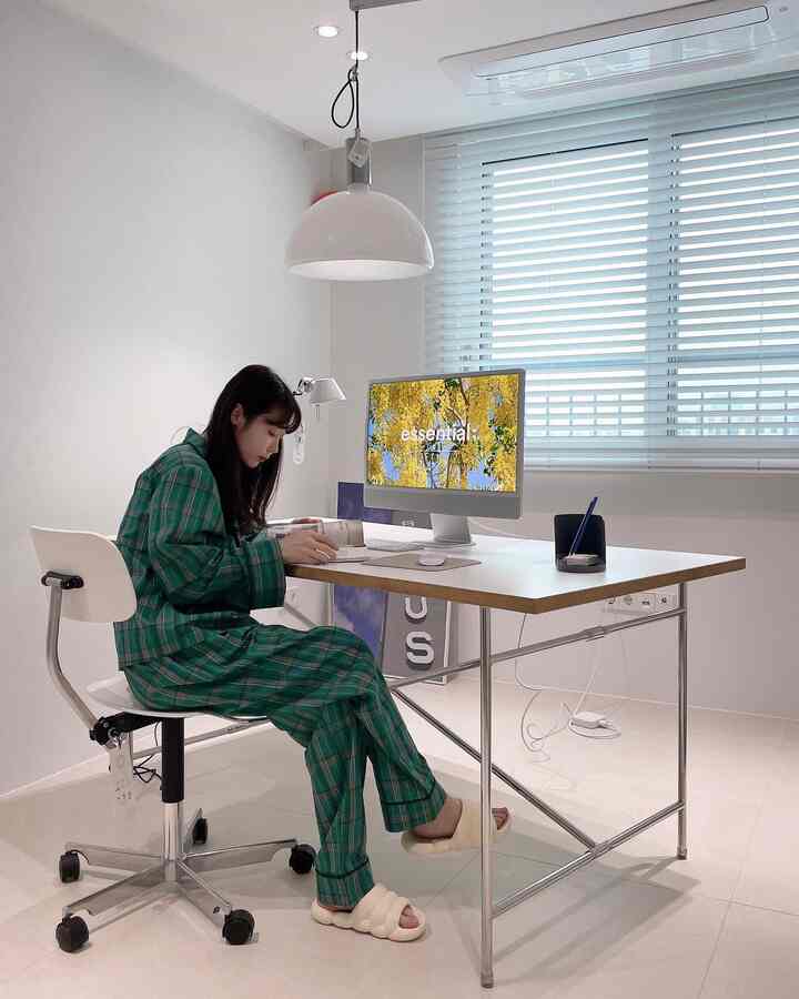 White-toned home office space featuring a clean desk, office chair, and pendant light with a simple modern interior