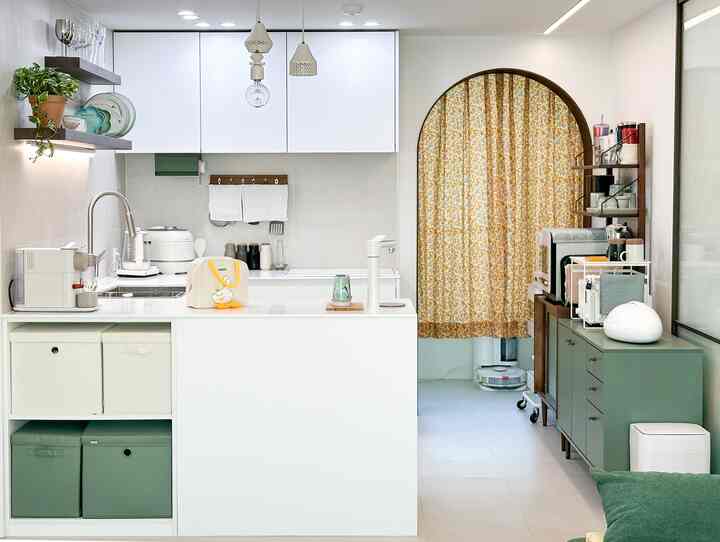 White and green toned kitchen featuring organized storage spaces and various kitchen utensils in a modern setting