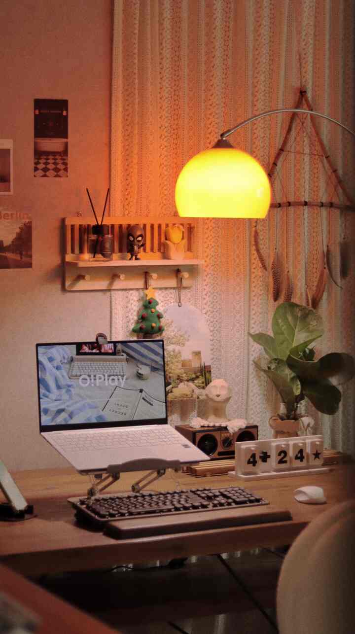 Natural tone home office space with warm yellow floor lamp lighting, wooden desk and plants creating a cozy workspace