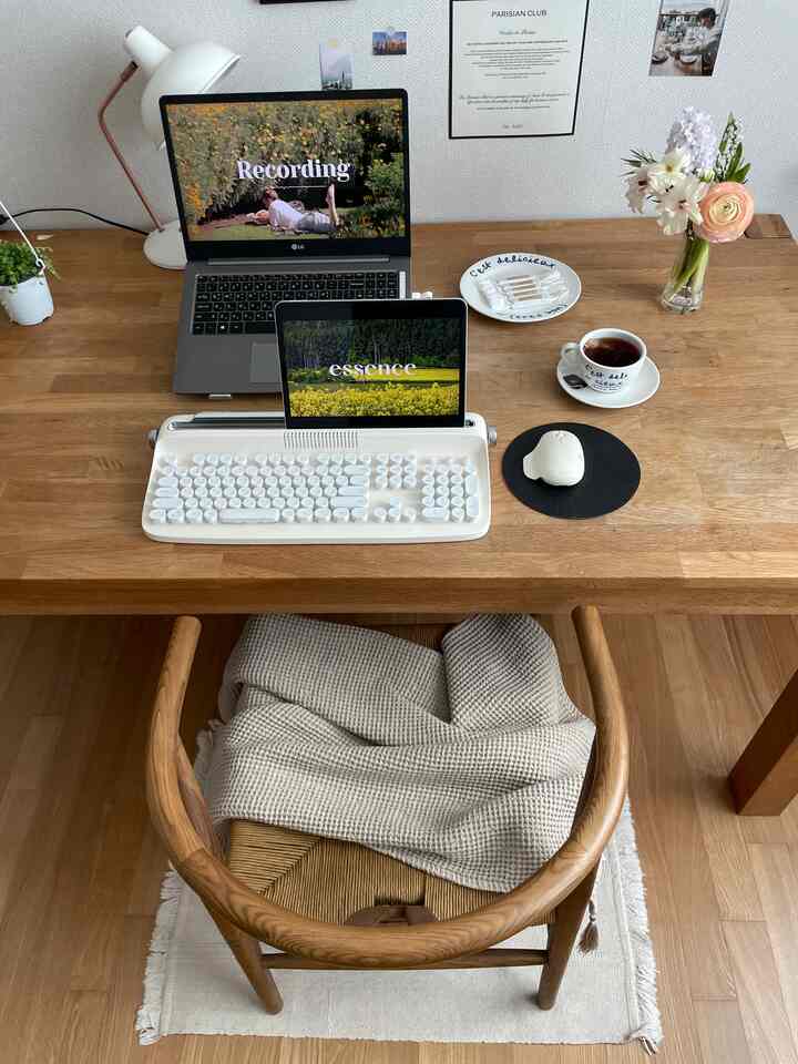 ナチュラルな木目調のホームオフィスデスク、ノートパソコンとキーボード、花瓶が配置された落ち着いた作業空間