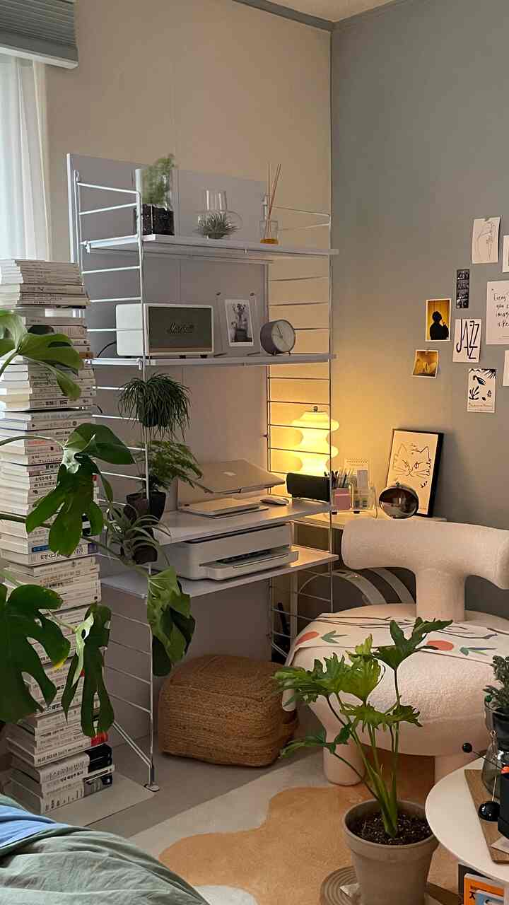 White and beige toned compact home office space featuring plants and bookshelves with a cozy work atmosphere