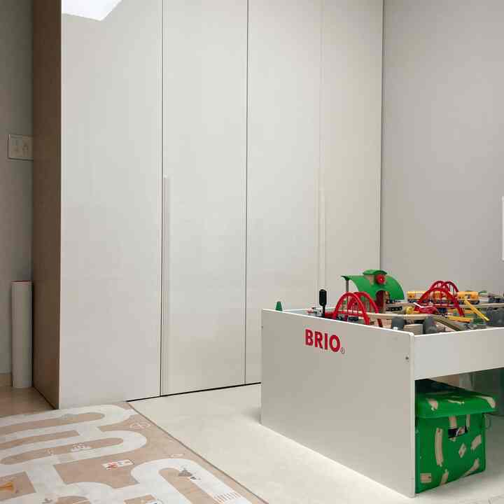 白を基調とした子供部屋、大型クローゼットとブリオのおもちゃテーブルが配置された雰囲気のある空間