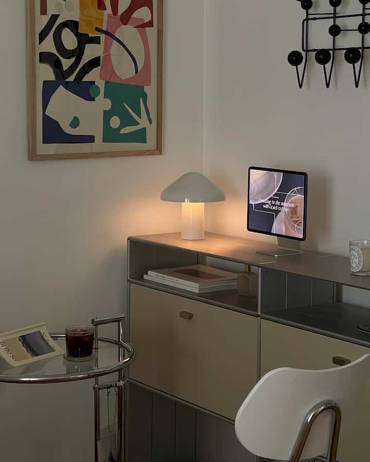 White and gray toned bedroom home office featuring wireless portable lamp and minimal side table in a simple setting
