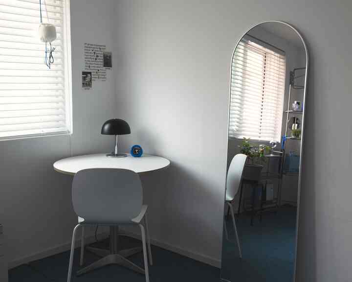 白と黒のトーンの小さな空間、アーチ型の全身鏡と円形テーブル、フロアランプが配置されたシンプルでモダンな部屋