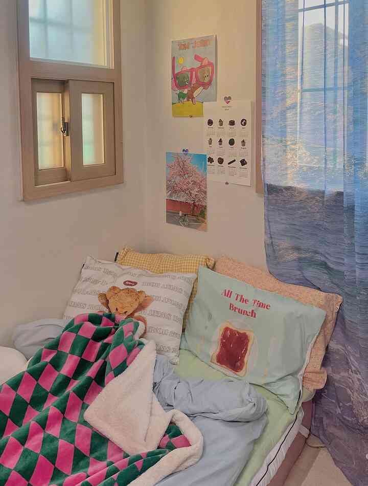 Pastel and blue toned studio bedroom featuring assorted pillows and a throw blanket, creating a cozy atmosphere