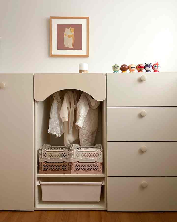 Beige-toned kids' room storage cabinets with hanging children's clothes and character toys neatly arranged in a tidy space