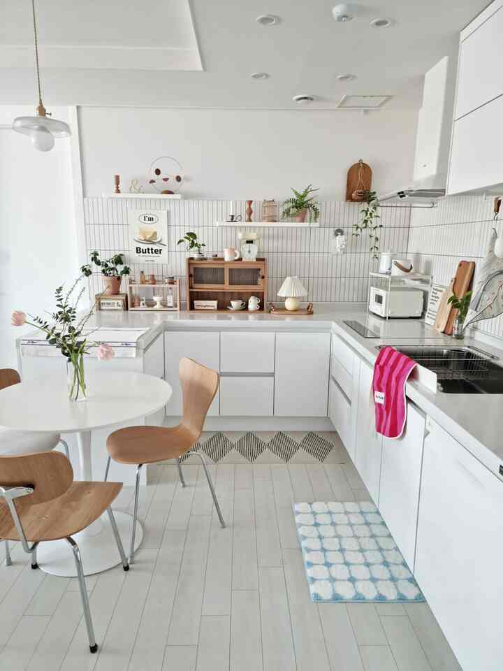 白と木目調が調和したシンプルモダンなキッチン、ダイニングチェアとラグが配置されて温かみのある印象的な空間