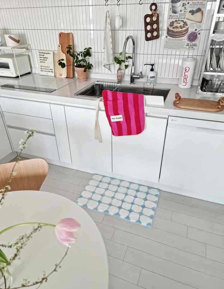 White and blue toned kitchen featuring sink, apron, and kitchen utensils with a neat, modern atmosphere