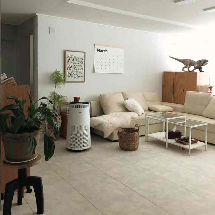 White and natural toned living room featuring cream sofa and white coffee tables in a neat minimal space