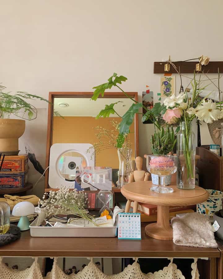 Cozy wood-tone tabletop space featuring various vases and plants with a wooden framed mirror