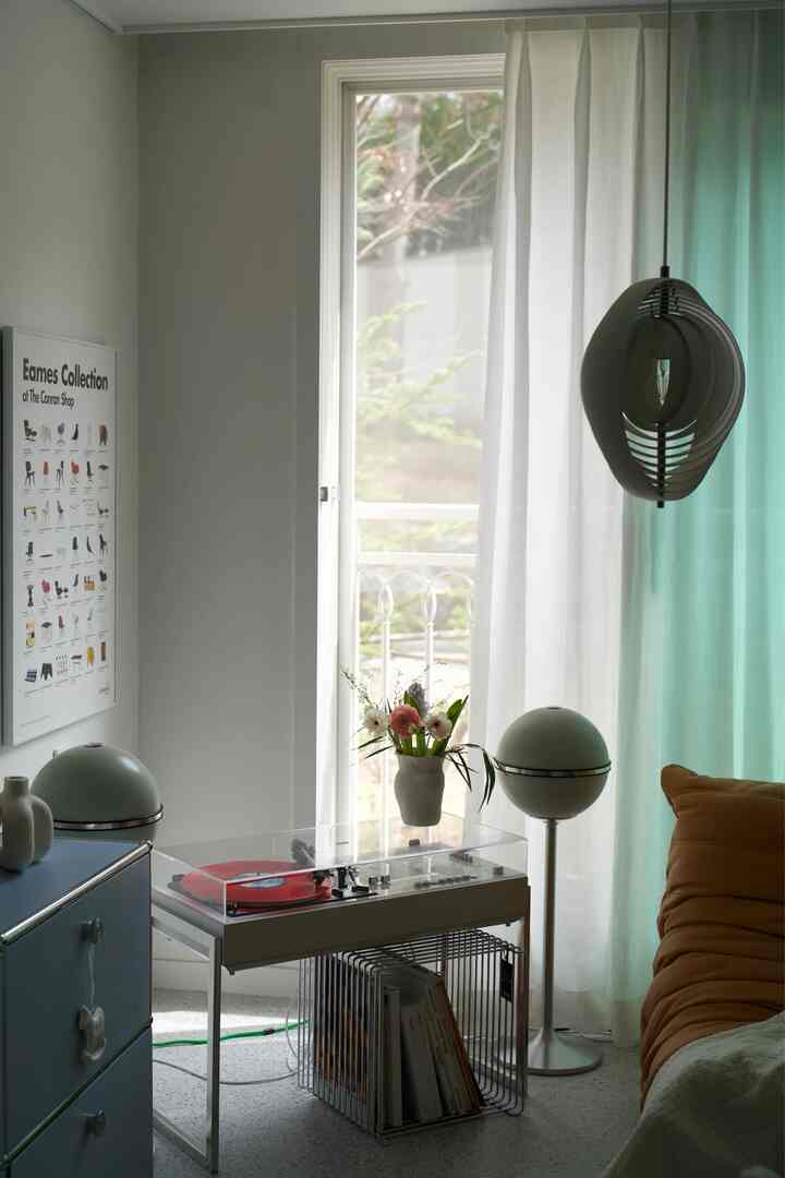 White and lavender living room featuring a vintage turntable, spherical speakers, and an orange sofa with natural light ambiance