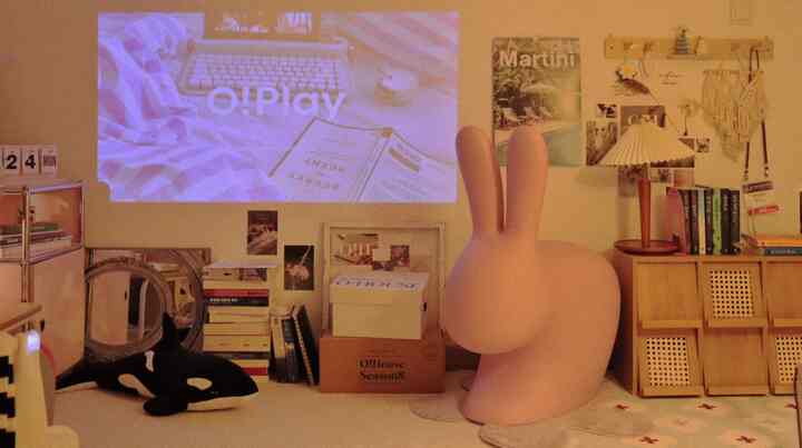 温かみのあるベージュ色調のホームシネマ空間、大きなウサギの椅子と本棚が配置された雰囲気のある部屋