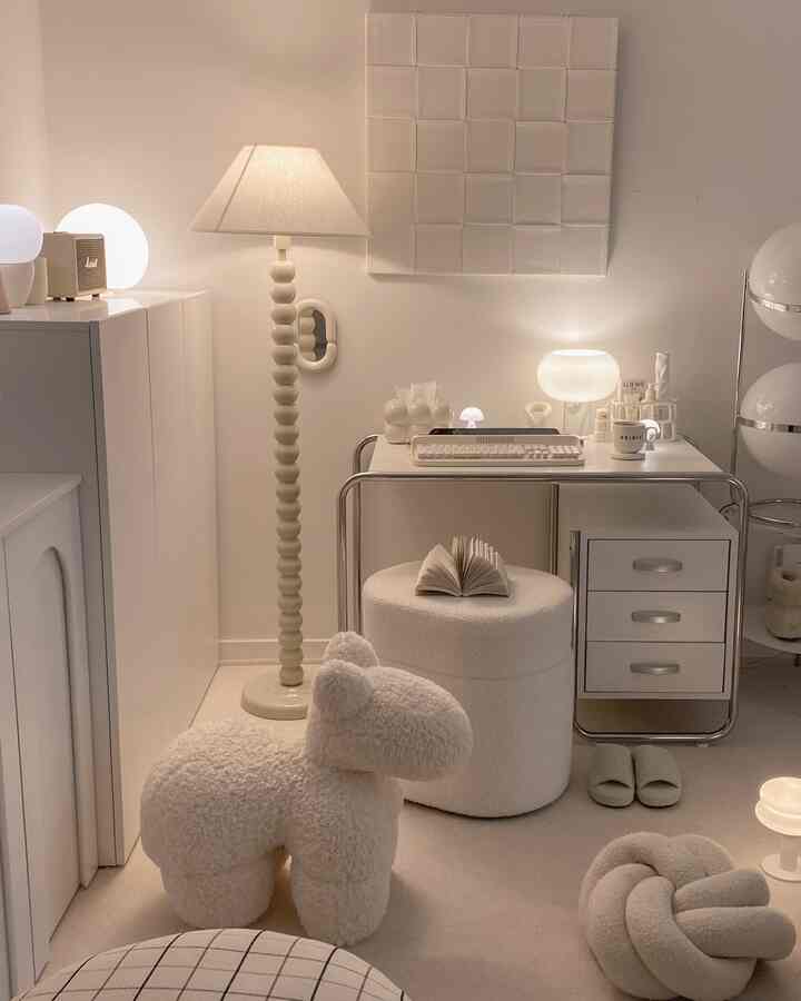 Soft white and beige toned multifunctional living room and home office featuring cushions and warm lighting for cozy atmosphere