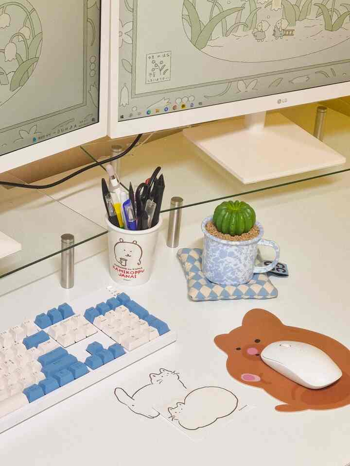 White and blue toned home office featuring cute cat illustrations and a small cactus on a clean desk