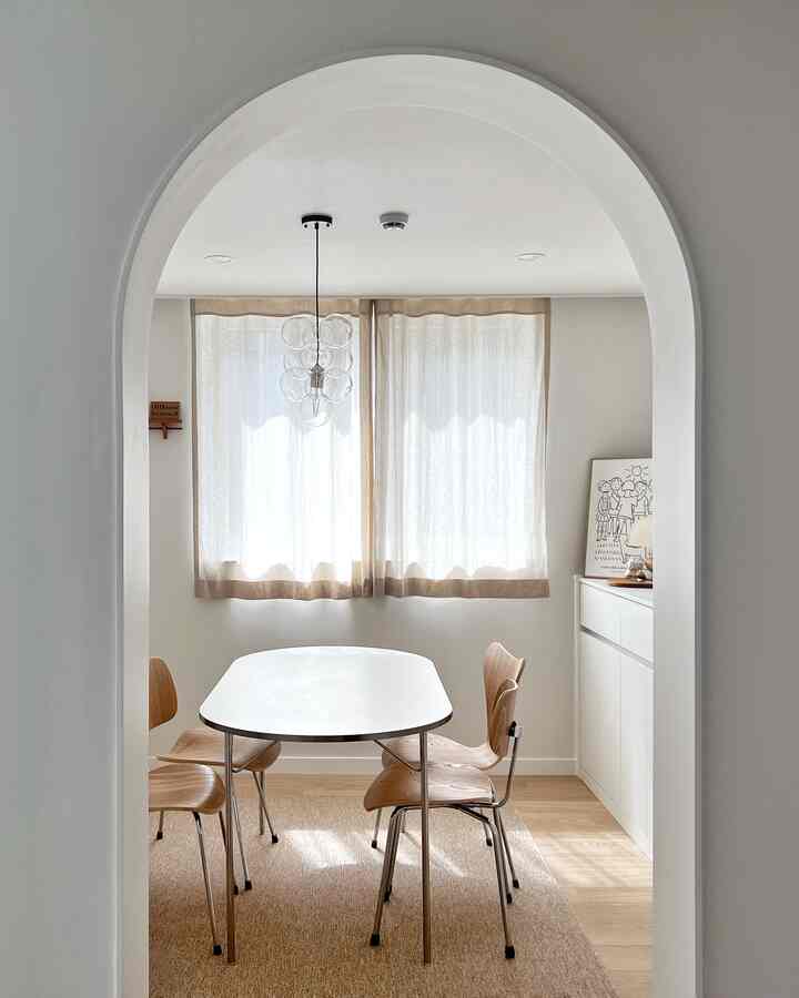 Natural dining room in white and wood tones, featuring a simple dining table and chairs in a cozy setting