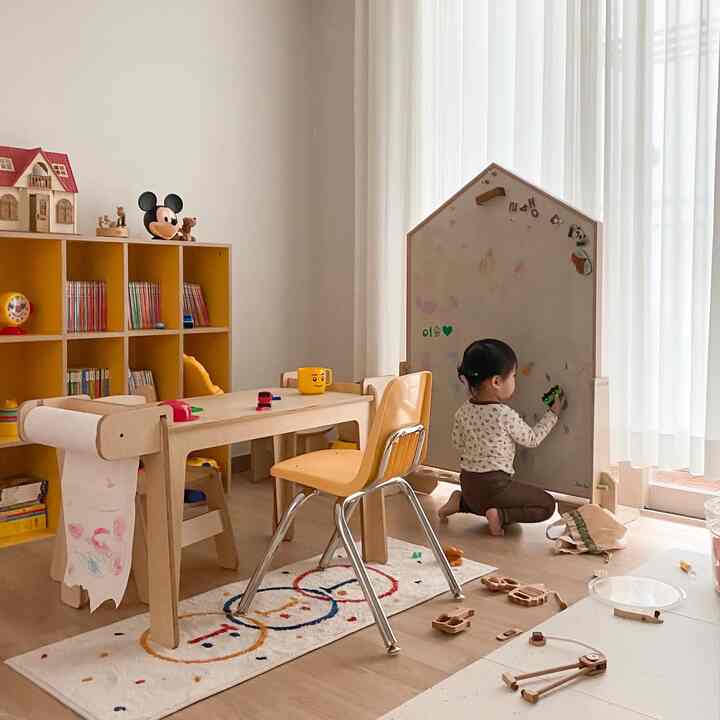 ナチュラルトーンの子供部屋、こども用机と本棚、マグネットボードが配置された暖かく居心地の良い空間