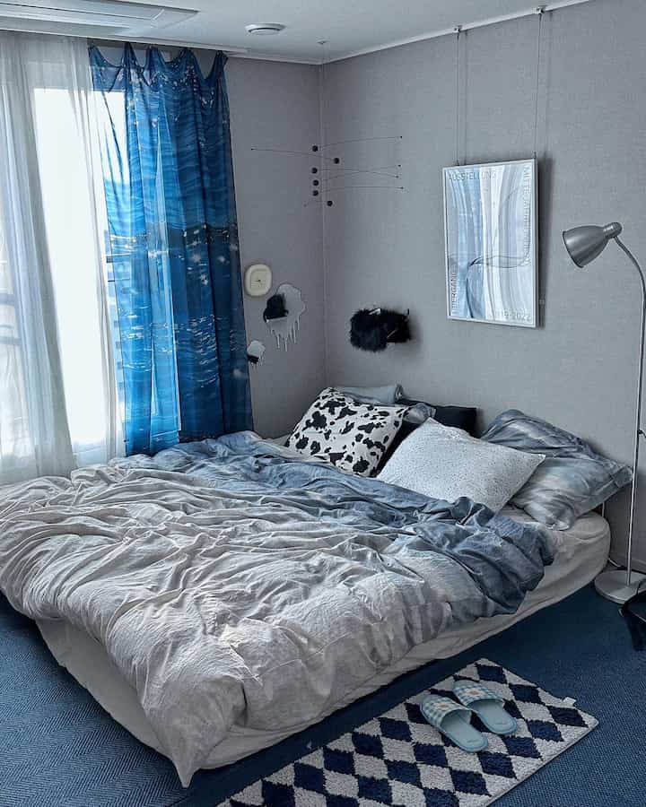 青色調の寝室、モビールと青いカーテンが配置された雰囲気のある空間